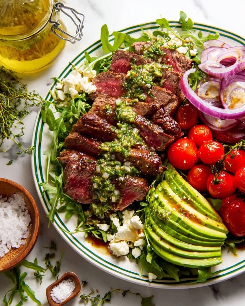 The image shows a white plate with a green rim placed on a white marbled surface. On the plate, there are several layers: at the base, fresh green arugula leaves spread across the plate; atop the greens, there are slices of medium-rare steak, cooked with a browned crust and pink center, topped with a chunky green herb sauce. To the right of the steak, there are bright red grape tomatoes still on the vine and thin slices of purple-red onion rings. Below the steak and tomatoes, there is a fan of sliced avocado in vibrant green with a drizzle of sauce. Near the edge of the plate, some white crumbly cheese is visible. Around the plate, scattered sprigs of fresh herbs, a small wooden bowl of coarse salt, and a clear jar of yellow vinaigrette with herbs sit on the white marbled surface. photo taken with an iphone --ar 4:5 --v 7