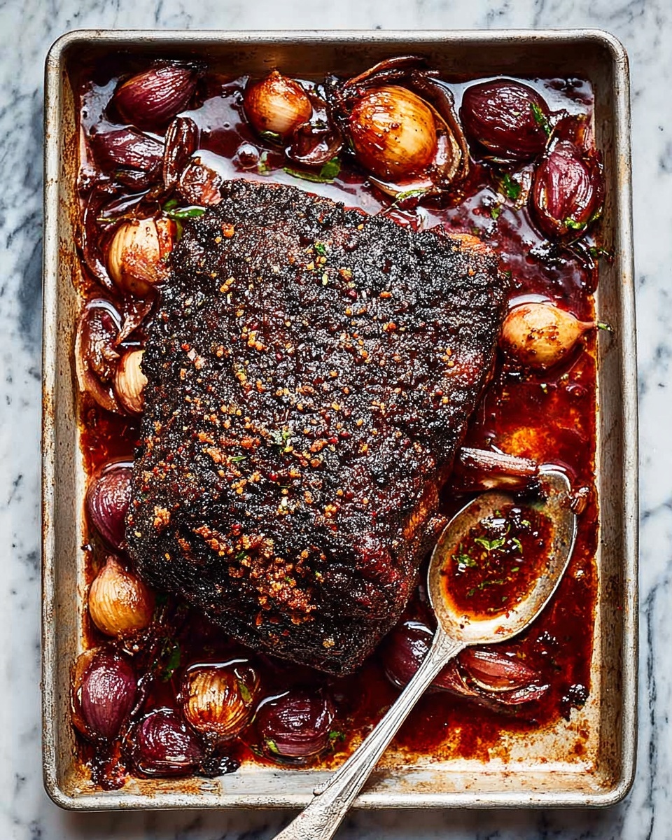 A large piece of roasted meat with a dark, crispy, charred crust sits in the center of a rectangular metal baking tray, surrounded by glossy, deep brown roasted onions and shallots. The meat has a rough texture with visible seasoning on top, and the tray contains rich, dark red juices pooling around the vegetables. A silver spoon with some sauce on it rests against the side of the tray. The tray is placed on a white marbled surface. Photo taken with an iphone --ar 4:5 --v 7