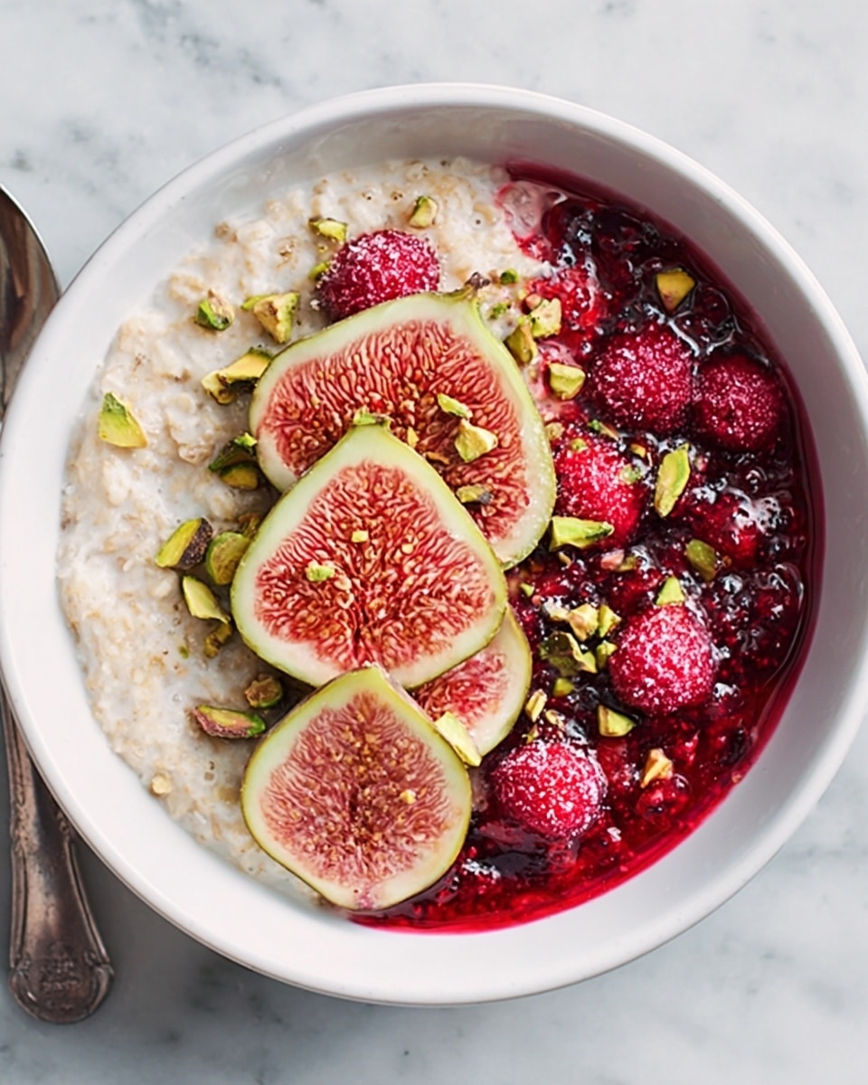 The image shows a white bowl filled with creamy oatmeal that takes up about half of the space on the left side. On the right side, there is a bright red berry sauce with whole raspberries mixed in, creating a vibrant contrast. In the middle, there are three thinly sliced fresh figs layered on top of the oatmeal, with their pinkish inner color and green edges visible. Scattered over the figs and berry sauce are small pieces of green pistachios, adding texture and color. The bowl is placed on a white marbled surface, and part of a spoon is visible in the corner. photo taken with an iphone --ar 4:5 --v 7