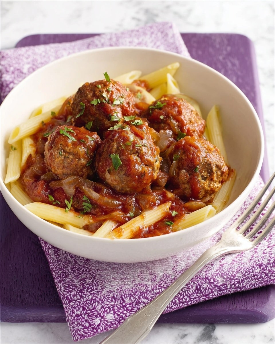A white bowl filled with penne pasta at the bottom, light yellow in color and slightly glossy from sauce. On top, there are five round meatballs, brown with a textured surface, covered in a thick reddish-brown tomato sauce with visible chunks of onions and herbs. Small green herbs are sprinkled over the top of the meatballs and sauce. The bowl sits on a white cloth with purple embroidery, which is placed over a purple wooden board. To the right of the bowl is a silver fork resting on the cloth. The background is a white marbled texture. Photo taken with an iphone --ar 4:5 --v 7
