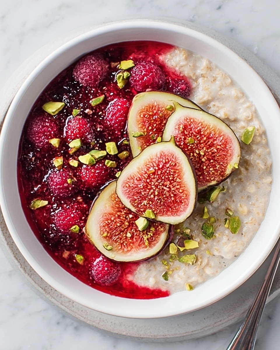 A white bowl filled with two main layers creates a delightful contrast. On the left side, there is a creamy, light beige oatmeal base with a smooth texture. On the right side, a bright red berry sauce with visible whole berries and seeds adds a juicy, slightly chunky texture. On top of the oatmeal, in the center, are four thin, oval slices of fresh fig with green skin and pink seedy inside. Scattered around the figs and over both layers are small, chopped green pistachios. The bowl is placed on a white marbled surface. photo taken with an iphone --ar 4:5 --v 7