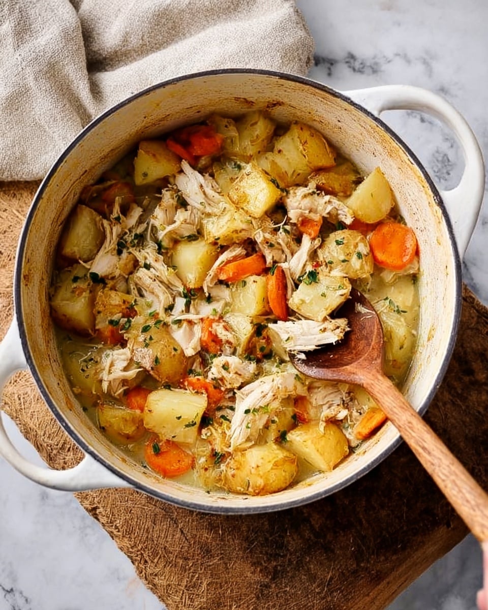 A white pot filled with a stew made of several layers: the bottom has chunky pieces of golden roasted potatoes with crispy edges; mixed throughout are tender, shredded chicken pieces in a light broth; bright orange carrot slices add color; bits of fresh herbs are scattered on top, giving a touch of green; a woman's hand holds a wooden spoon resting inside the pot. The pot sits on a textured wooden board, placed on a white marbled surface with a soft beige cloth in the background. photo taken with an iphone --ar 4:5 --v 7