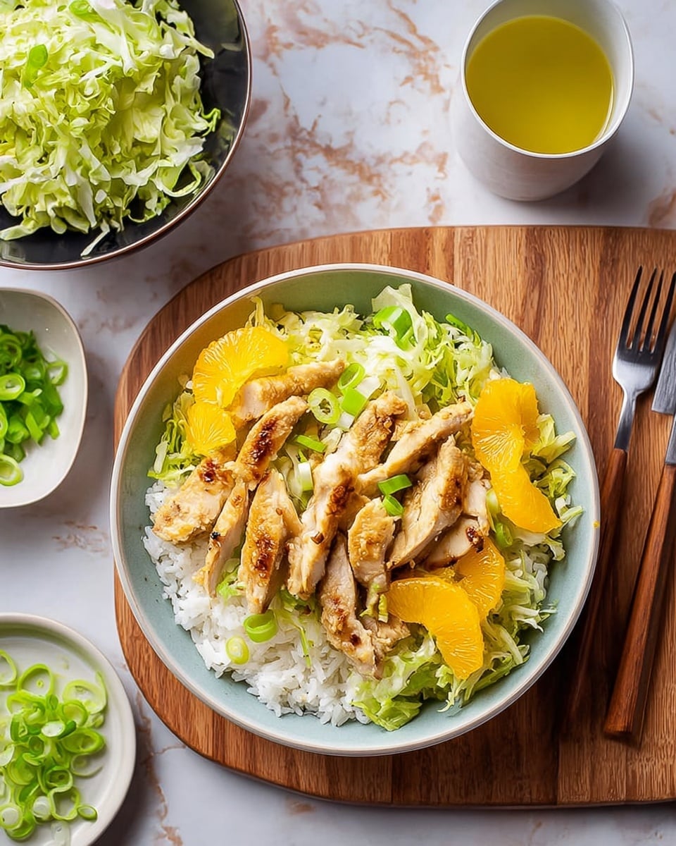 A white bowl sits on a wooden board over a white marbled texture, filled with three main layers: at the bottom is a bed of white cooked rice with fluffy texture, followed by a layer of shredded light green lettuce spread evenly on the rice. On top are light golden-brown pieces of cooked chicken, slightly crispy with visible grill marks, interspersed with small bright orange wedges of orange fruit and thin green slices of scallions scattered over. To the left, a black bowl holds more shredded lettuce, and above it, a small white plate contains extra thinly sliced green scallions. To the right of the bowl, there is a fork and a white cup with a yellow-green liquid inside. photo taken with an iphone --ar 4:5 --v 7