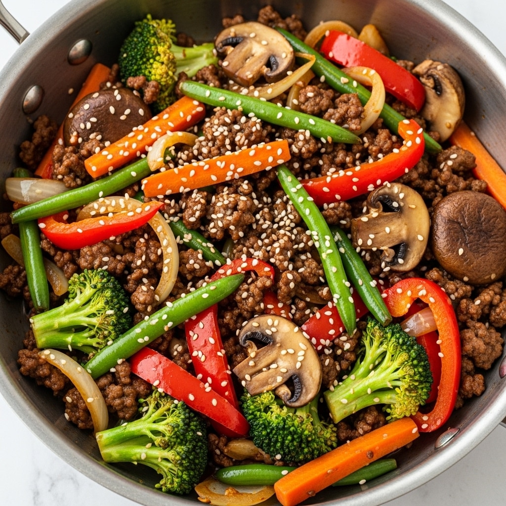 A close-up top view of a pot filled with a colorful stir-fry mix consisting of cooked ground meat, sliced brown mushrooms coated in sauce and sprinkled with white sesame seeds, bright green beans, red bell pepper strips, orange carrot slices, broccoli florets, and translucent cooked onions. The vegetables and meat pieces are mixed evenly throughout the dish, creating a rich texture with shiny, saucy areas and matte cooked bits all combined. The pot is stainless steel and sits on a white marbled background. Photo taken with an iphone --ar 4:5 --v 7