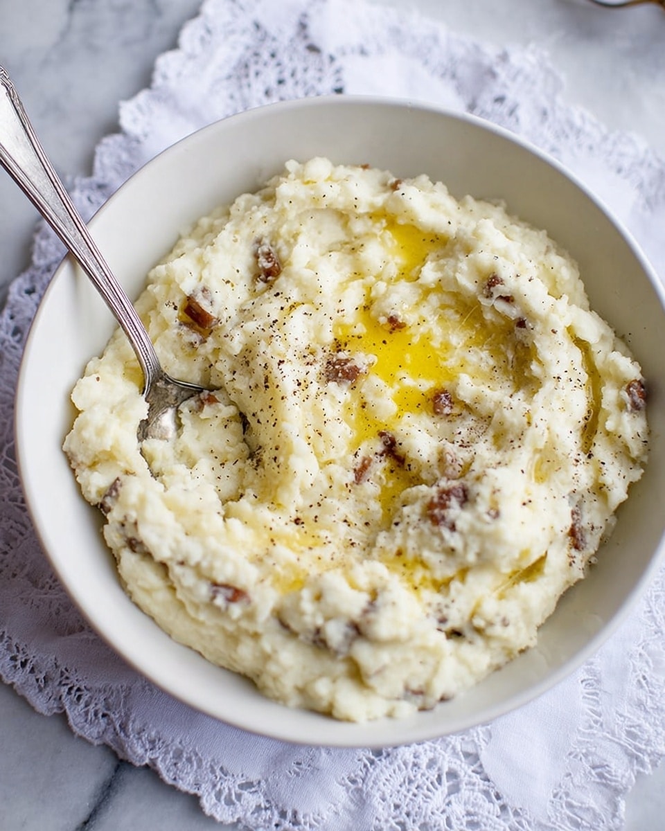 A white bowl filled with creamy grits that have a slightly lumpy texture, mixed with bits of light brown sausage. On top, there is a small pool of melted yellow butter spreading over the surface, sprinkled lightly with black pepper. A silver spoon is placed inside the bowl on the right side, partly covered by the grits. The bowl is sitting on a white marbled texture with a white cloth featuring cut-out patterns beneath it. photo taken with an iphone --ar 4:5 --v 7