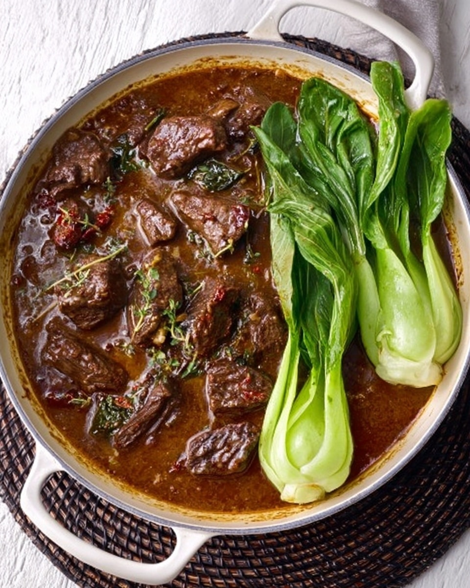The image shows a white pan filled with a rich brown stew containing chunks of tender meat scattered throughout, covered in a glossy sauce with visible herbs and spices. On one side of the pan, there are two fresh, bright green bok choy leaves resting gently on top of the stew. The pan sits on a dark woven mat placed on a white marbled surface. The whole scene is lit softly to highlight the textures of the meat and the shiny leaves. photo taken with an iphone --ar 4:5 --v 7