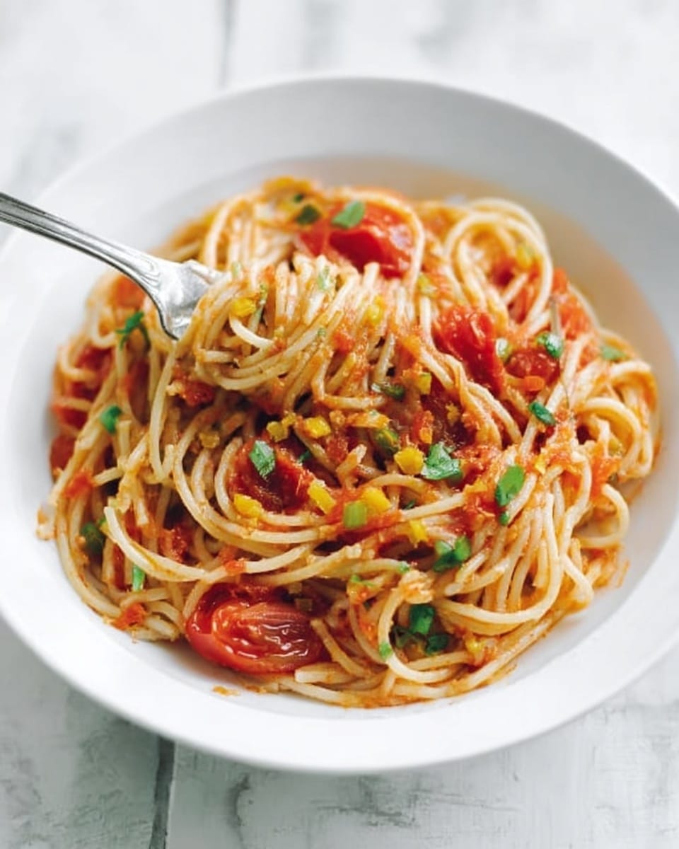 A white plate holds a serving of spaghetti mixed with red tomato sauce, scattered with green herbs and small yellowish bits that could be cheese or vegetable pieces, creating a mix of red, green, and yellow colors. The spaghetti strands are lightly coated with sauce, and on top, there are whole pieces of tomato adding a fresh texture. A metal fork rests in the dish, partially inserted into the pasta, all placed on a white marbled surface. photo taken with an iphone --ar 4:5 --v 7